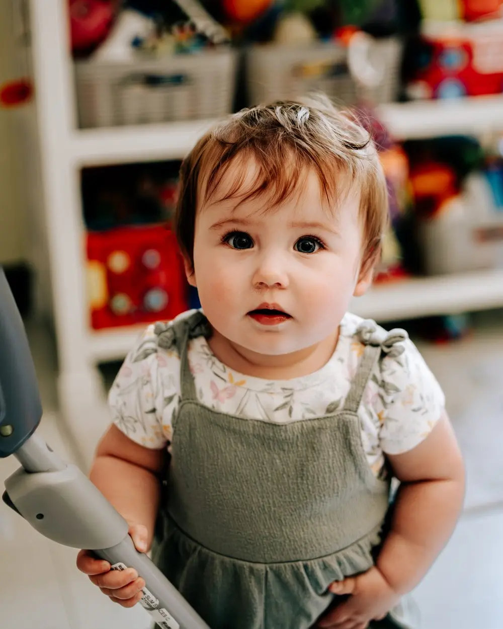 A baby in green overalls looking up at the camera