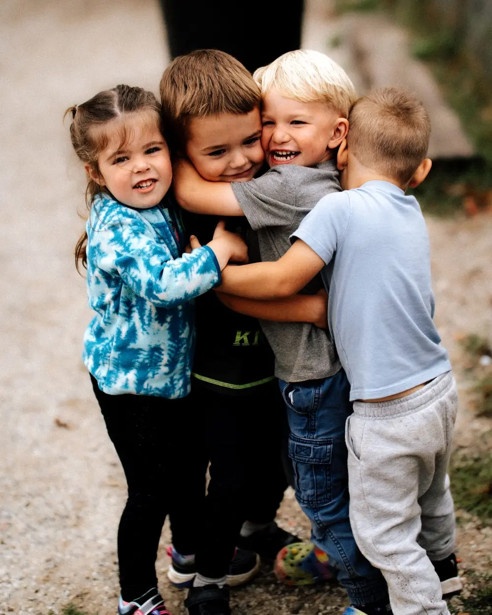 Four Kids & Co. children in a group hug outside